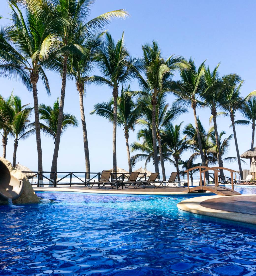 Alberca y palmeras de Be Beach Club frente al mar